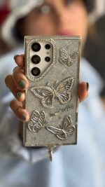 قاب موبایل ( آیفون - سامسونگ ) پروانه آموره نگین دار برجسته شاینی + بندست - تصویر 3
