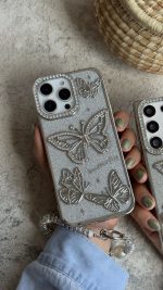 قاب موبایل ( آیفون - سامسونگ ) پروانه آموره نگین دار برجسته شاینی + بندست